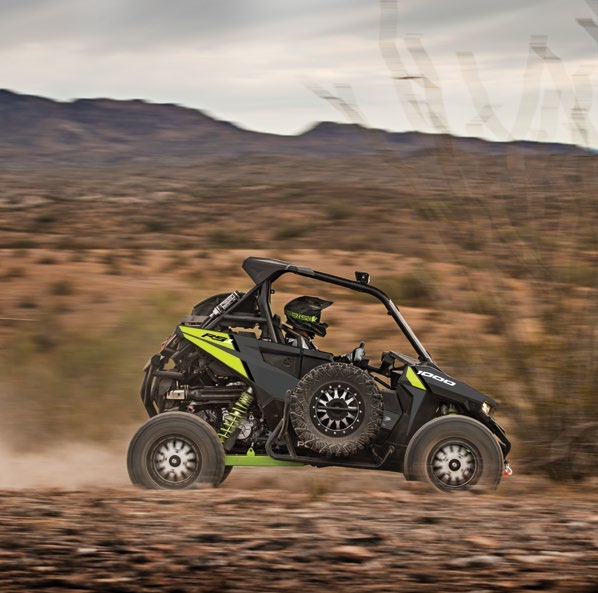 Polaris RZR RS1 with centered driver and side-mounted spare tire, complete vehicle on a dirt trail