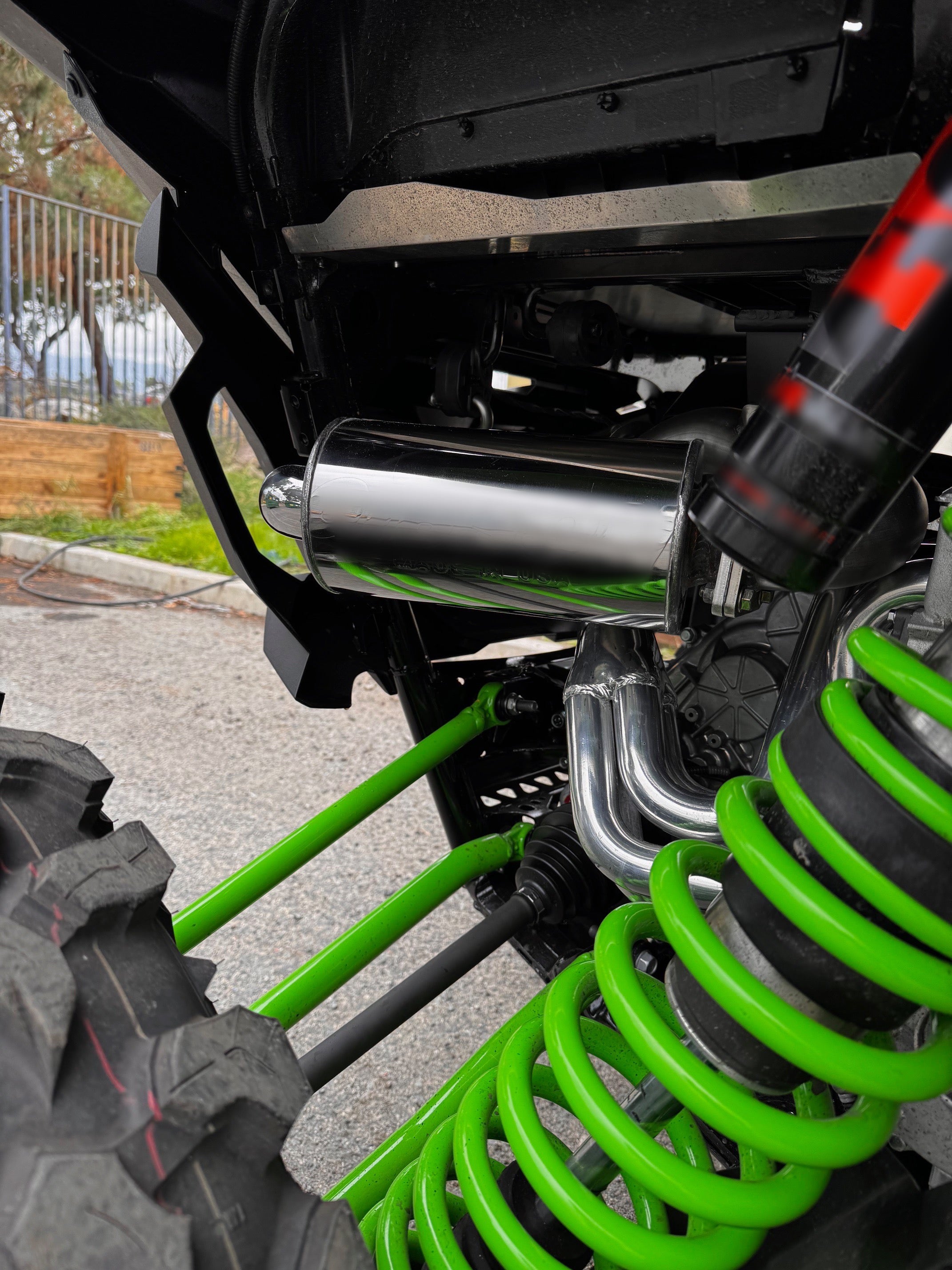 Kawasaki TERYX4 H2 close-up showing the performance exhaust system and green suspension springs from a right-side angle, highlighting Fast UTV’s full installation quality.