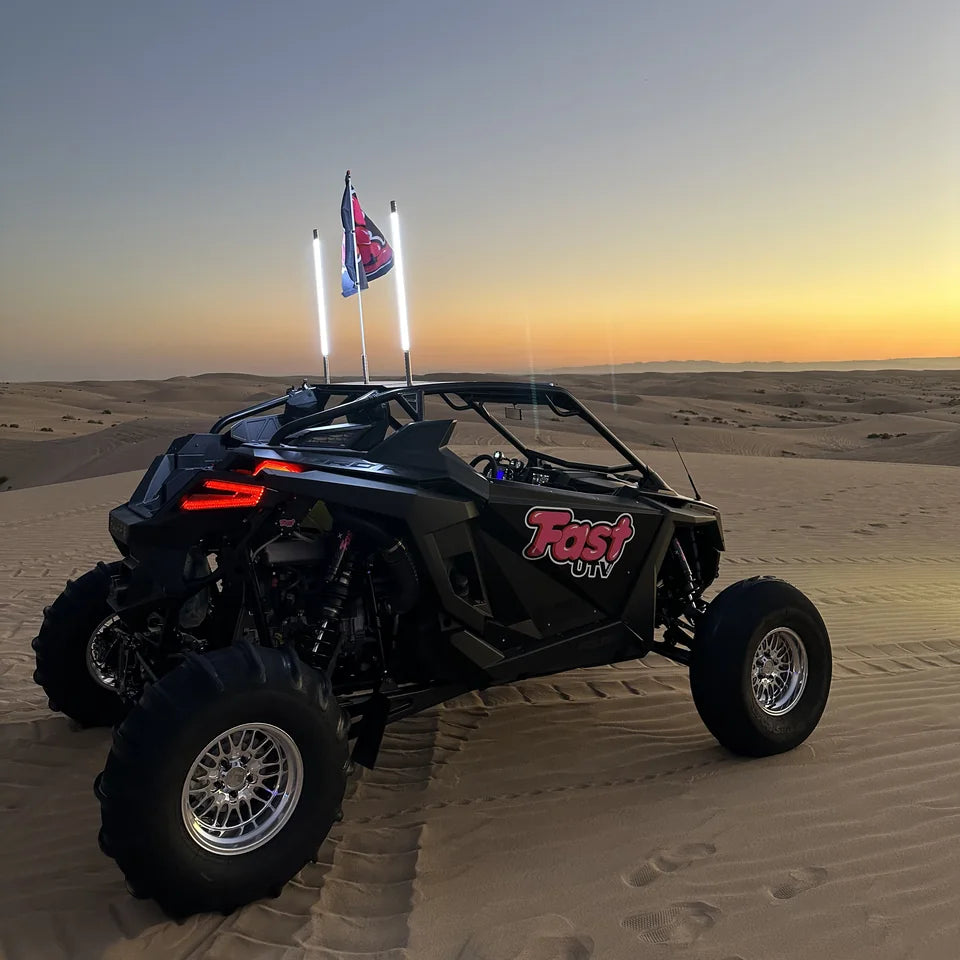 Complete FastUTV UTV with paddle tires and a flag on sand at dusk